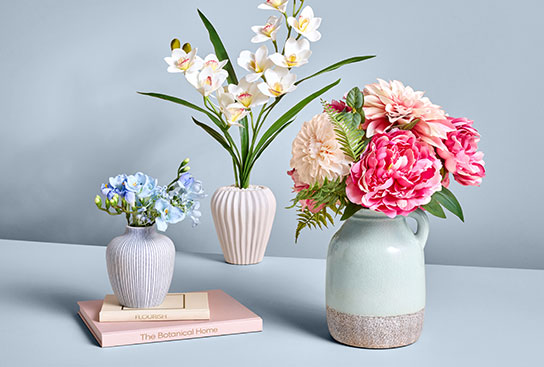An array of vibrant faux floral arrangements in textured vases.